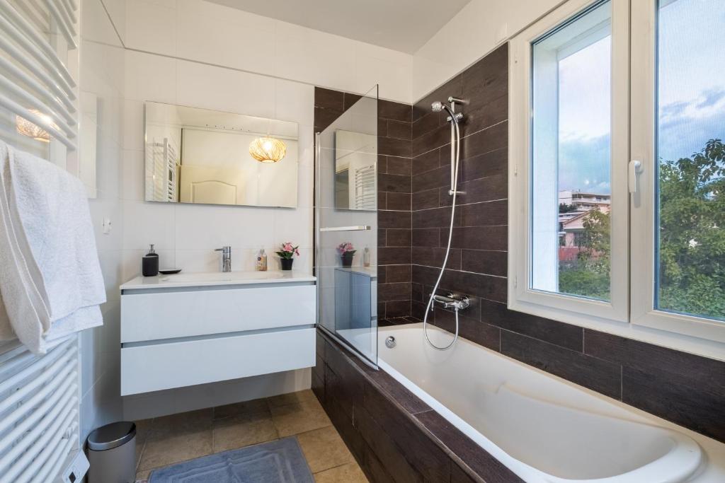 Salle de bains avec baignoire, douche et fenêtre de la Villa Nelys