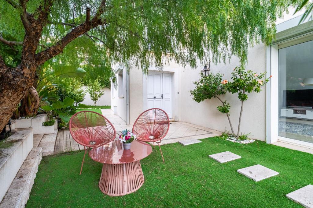 Patio ombragé avec fauteuils et pelouse de la Villa Nelys